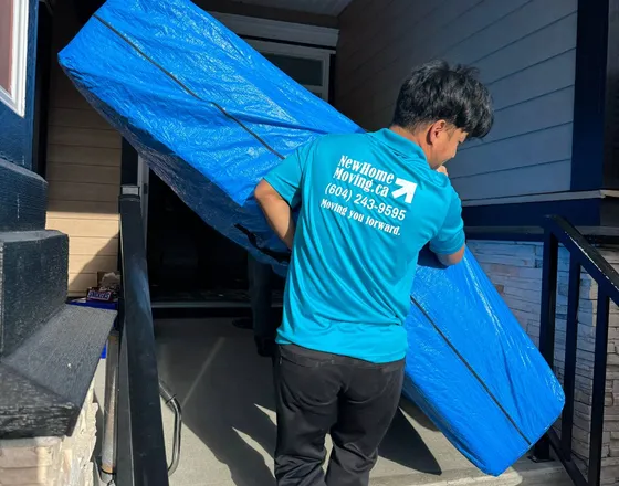 New Home Moving crew carrying wrapped furniture down front steps