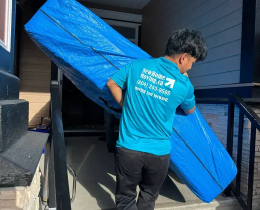 New Home Moving crew carrying wrapped furniture down front steps