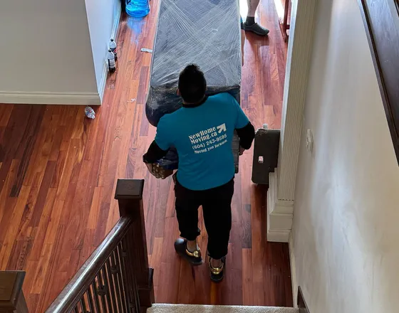 Movers carrying a mattress down a stairwell