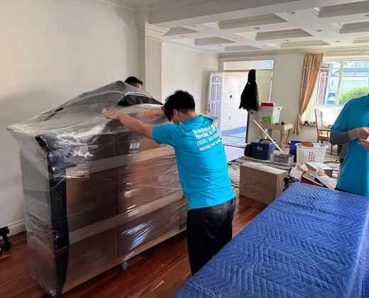 Mover wrapping a dresser in protective shrink wrap before a move