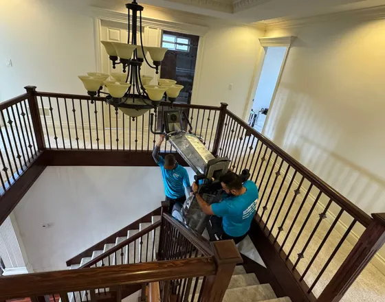 Movers carrying a large item down a flight of stairs
